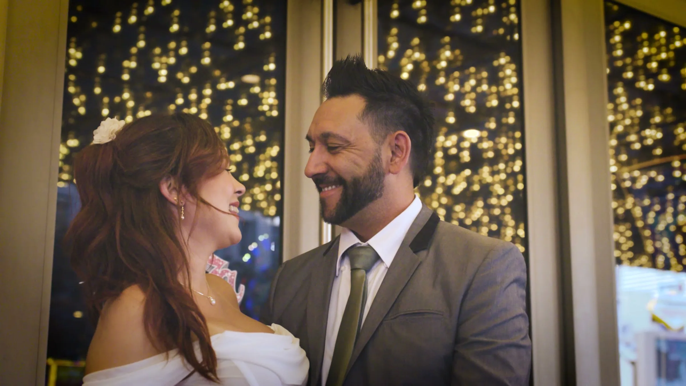 Luciano and Muriel laughing together under the gold marquee lights
